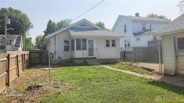 rear view of property featuring a fenced backyard, a lawn, and roof with shingles