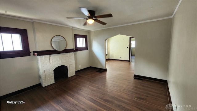 unfurnished living room with baseboards, dark wood finished floors, arched walkways, ornamental molding, and a fireplace