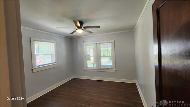 empty room with ceiling fan, dark wood-style flooring, visible vents, baseboards, and ornamental molding