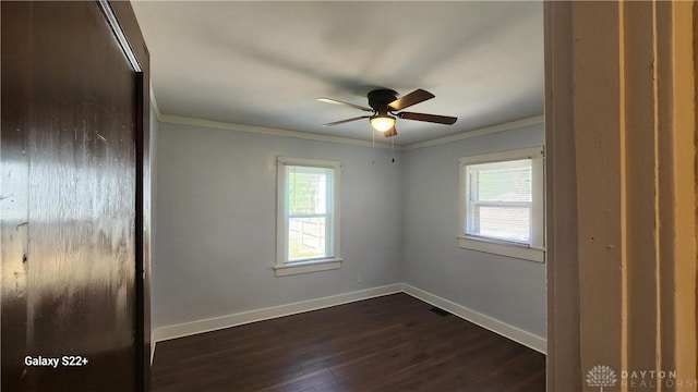 spare room featuring a healthy amount of sunlight, baseboards, dark wood-type flooring, and crown molding