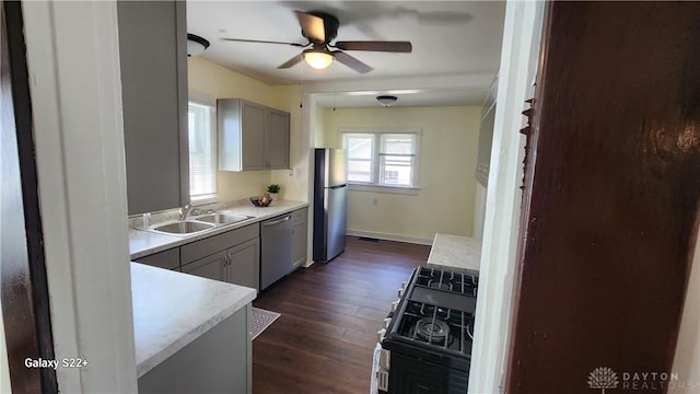 kitchen with dark wood-style floors, appliances with stainless steel finishes, light countertops, gray cabinetry, and a sink