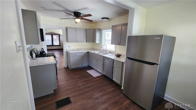 kitchen featuring dark wood-style flooring, stainless steel appliances, gray cabinets, visible vents, and a sink