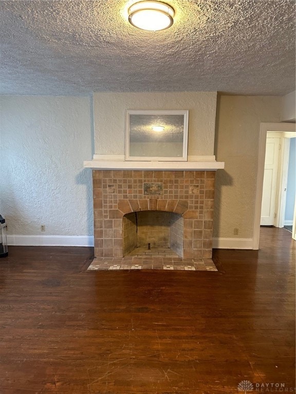 unfurnished living room with a textured ceiling, dark wood-type flooring, and a tile fireplace