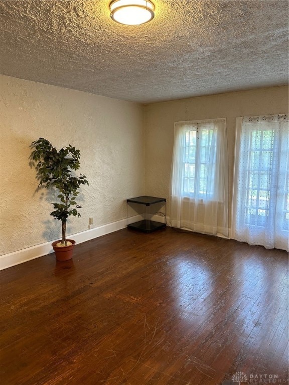 unfurnished room with a textured ceiling and dark hardwood / wood-style flooring