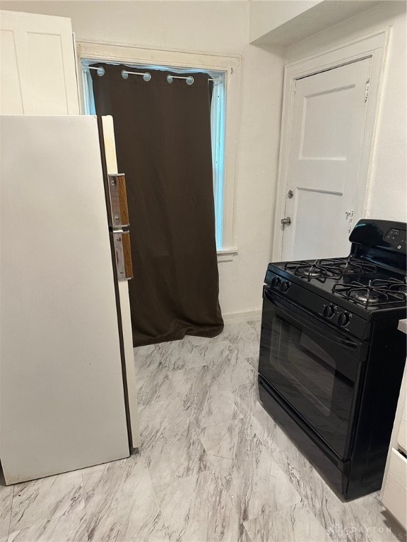 kitchen featuring white cabinetry, white refrigerator, black gas range, and light tile patterned flooring