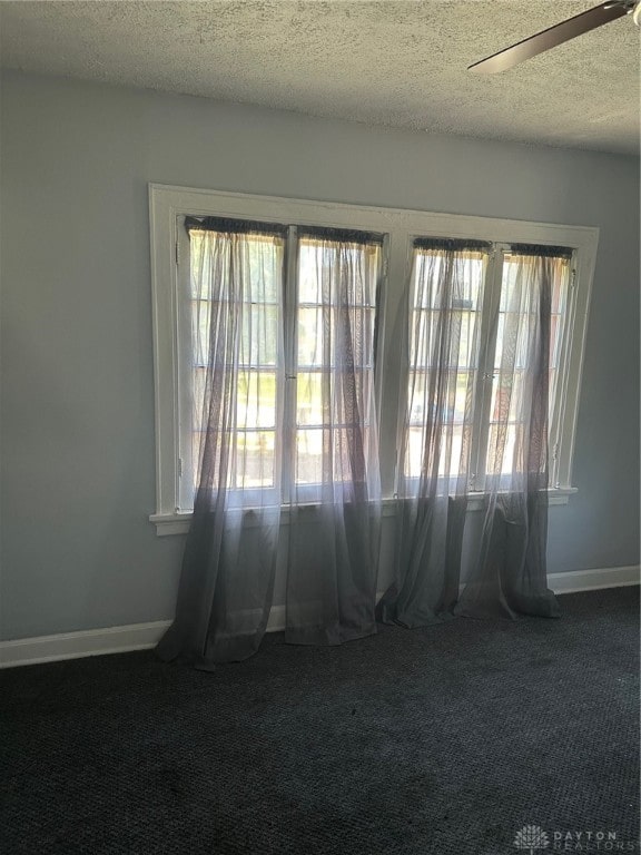 carpeted empty room with ceiling fan and a textured ceiling