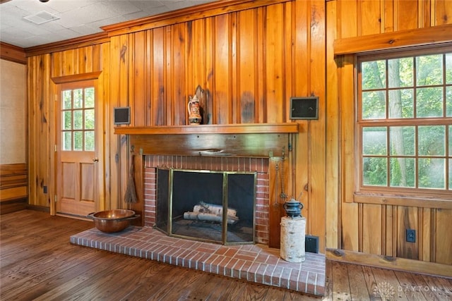 room details featuring crown molding, a fireplace, visible vents, wood walls, and wood finished floors