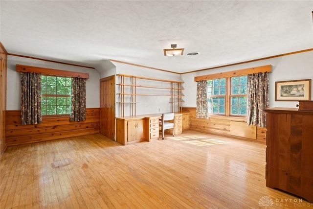 interior space featuring wainscoting, wood-type flooring, visible vents, and a healthy amount of sunlight