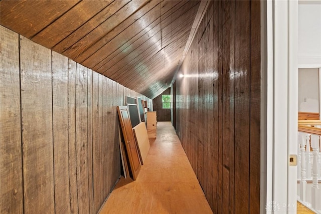 corridor with lofted ceiling, wooden ceiling, and wooden walls