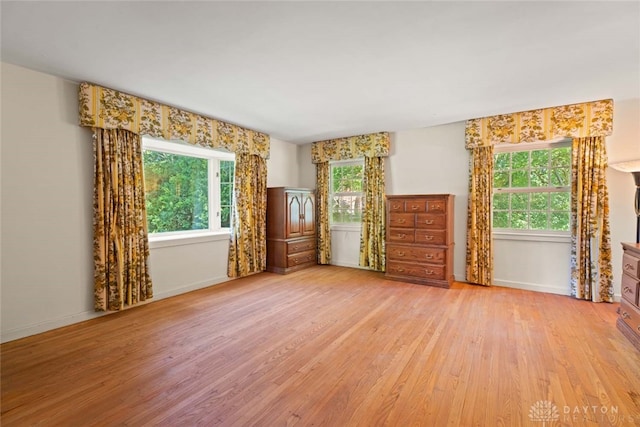 spare room featuring light wood-type flooring, plenty of natural light, and baseboards