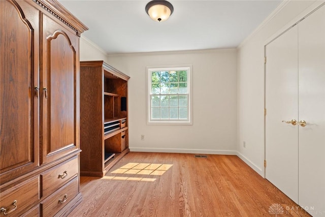 unfurnished bedroom featuring light wood-style floors, visible vents, crown molding, and baseboards