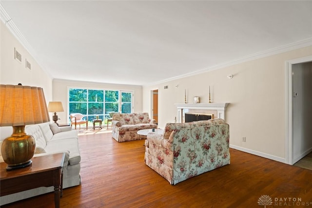 living room featuring baseboards, visible vents, ornamental molding, wood finished floors, and a fireplace