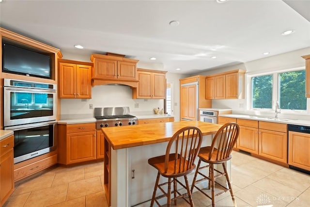 kitchen with recessed lighting, stainless steel appliances, a breakfast bar, a kitchen island, and wooden counters