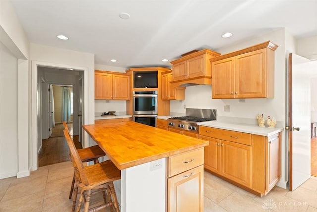 kitchen with a breakfast bar area, stainless steel appliances, recessed lighting, wooden counters, and a kitchen island