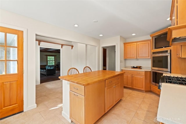 kitchen featuring butcher block counters, double oven, light brown cabinets, and recessed lighting