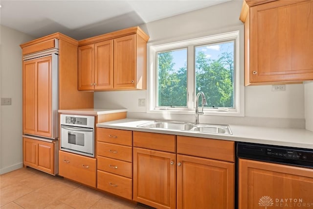 kitchen with paneled dishwasher, light countertops, oven, and a sink