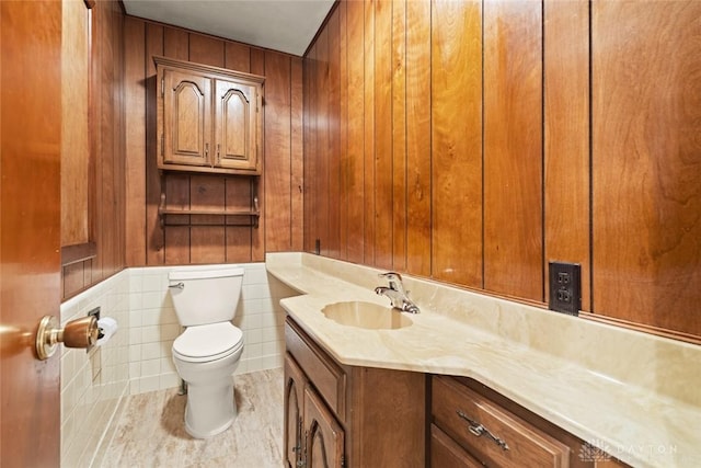 bathroom featuring toilet, wood walls, and vanity