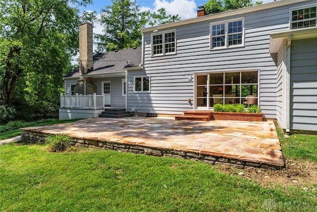 back of house with a yard, a chimney, a patio area, and a wooden deck