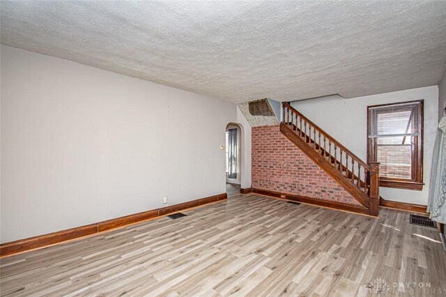 unfurnished living room featuring a textured ceiling and light hardwood / wood-style flooring