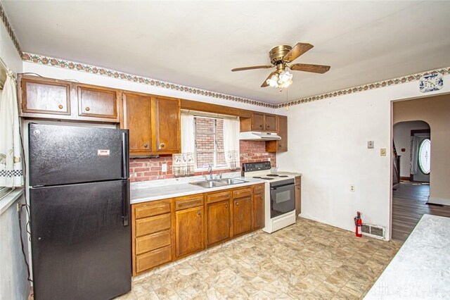 kitchen featuring decorative backsplash, black fridge, ceiling fan, sink, and electric range