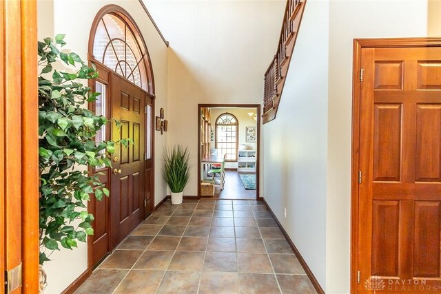 entryway featuring a towering ceiling and dark tile patterned flooring