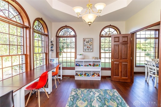 office with a raised ceiling, dark wood-type flooring, and a chandelier