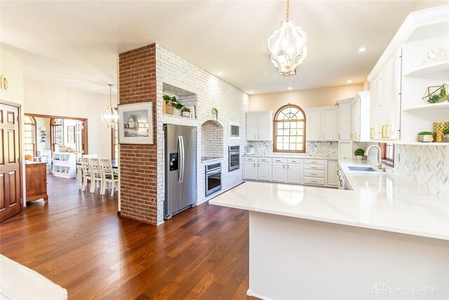 kitchen featuring kitchen peninsula, appliances with stainless steel finishes, dark hardwood / wood-style floors, and pendant lighting