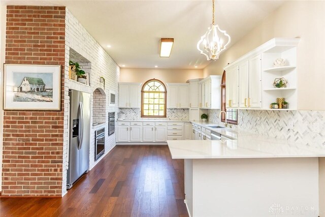 kitchen featuring white cabinetry, stainless steel appliances, dark hardwood / wood-style flooring, kitchen peninsula, and pendant lighting