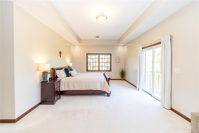 carpeted bedroom featuring a tray ceiling and access to exterior