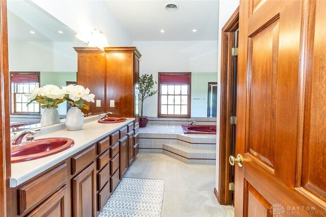 bathroom with tiled bath and vanity