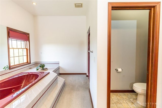 bathroom with a relaxing tiled tub and toilet