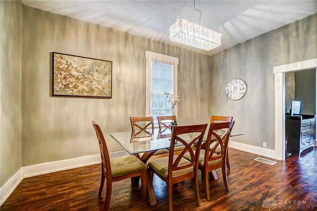 dining area with a notable chandelier and dark hardwood / wood-style flooring