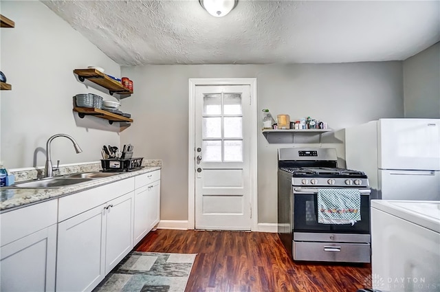 kitchen featuring white cabinetry, sink, dark wood-type flooring, white fridge, and stainless steel gas range oven