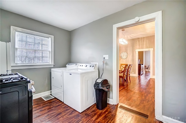 clothes washing area with dark hardwood / wood-style floors and separate washer and dryer