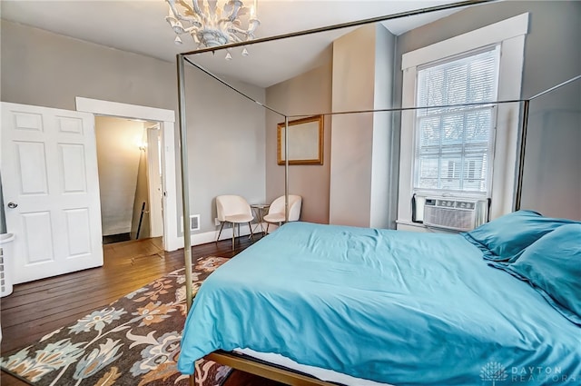 bedroom featuring cooling unit, a chandelier, and wood-type flooring