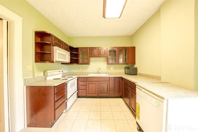 kitchen featuring sink, white appliances, a textured ceiling, light tile patterned floors, and kitchen peninsula