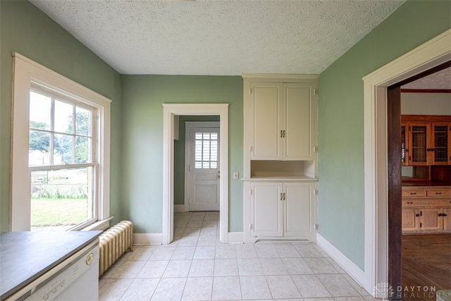 interior space featuring a textured ceiling, radiator, and light tile patterned floors