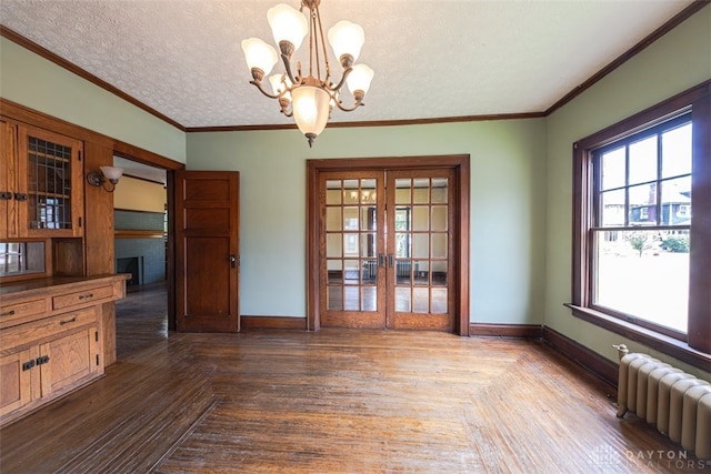 unfurnished dining area featuring radiator, french doors, a notable chandelier, a textured ceiling, and crown molding