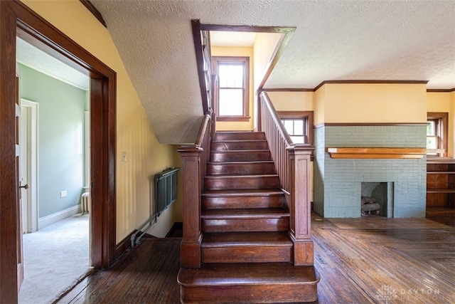 staircase featuring a fireplace, a textured ceiling, and carpet floors