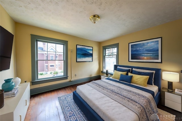 bedroom featuring a textured ceiling, hardwood / wood-style floors, and multiple windows