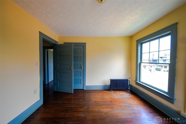 unfurnished bedroom with hardwood / wood-style flooring, a textured ceiling, and radiator