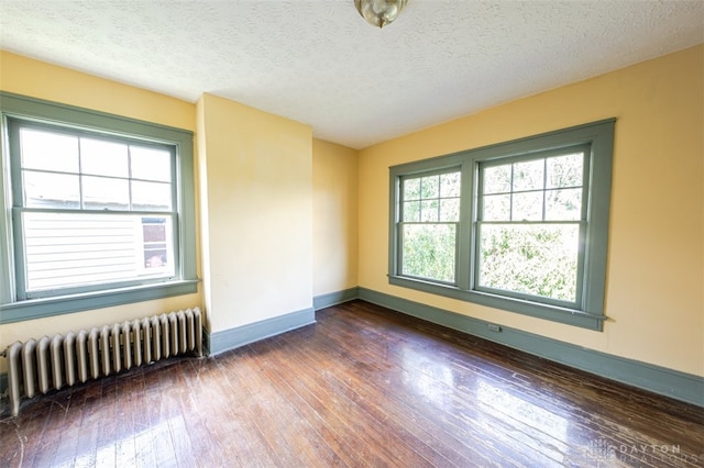 spare room featuring dark hardwood / wood-style floors, a textured ceiling, and radiator