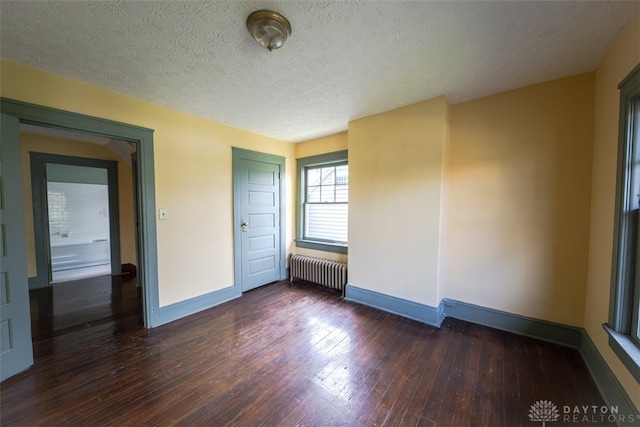 spare room featuring hardwood / wood-style flooring, a textured ceiling, and radiator heating unit