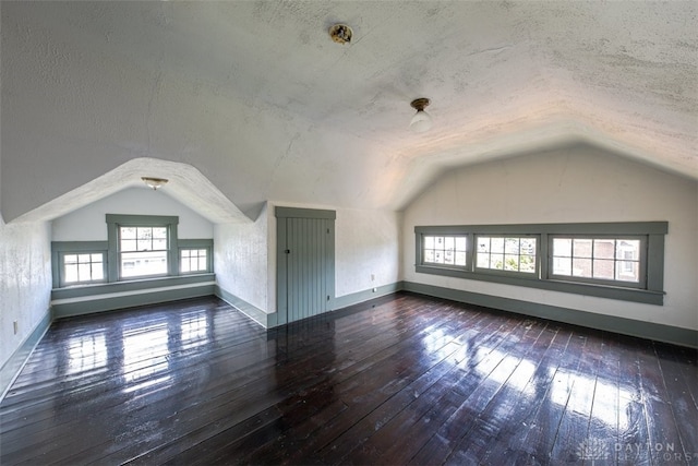 bonus room featuring hardwood / wood-style flooring, a textured ceiling, and lofted ceiling