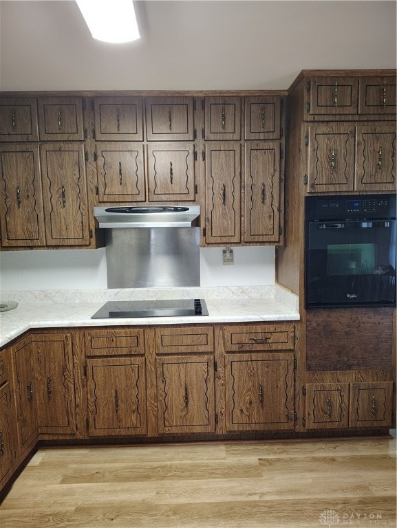 kitchen with cooktop, light hardwood / wood-style floors, and oven