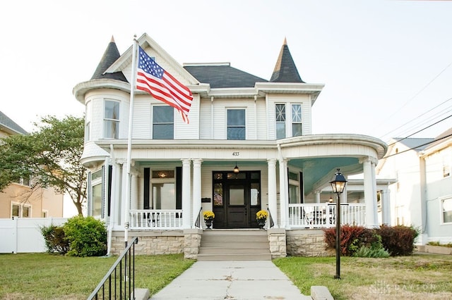 victorian house featuring covered porch and a front lawn