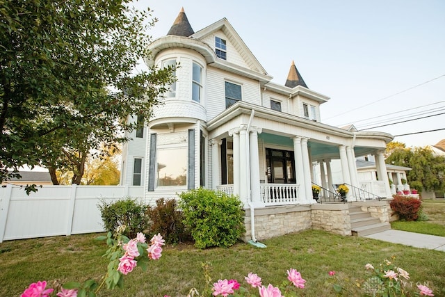 victorian house with a porch and a front lawn