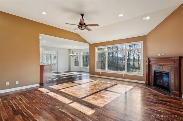 unfurnished living room with ceiling fan with notable chandelier, dark hardwood / wood-style floors, and vaulted ceiling