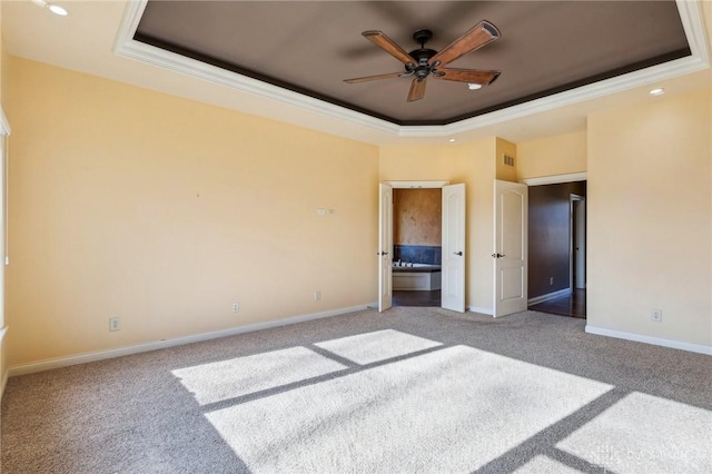 unfurnished bedroom featuring a tray ceiling, carpet floors, crown molding, and ceiling fan