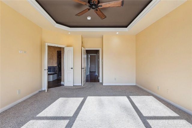 unfurnished bedroom featuring carpet flooring, ensuite bathroom, ornamental molding, and a tray ceiling